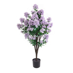 Artificial purple flowering plant in a pot on a white background
