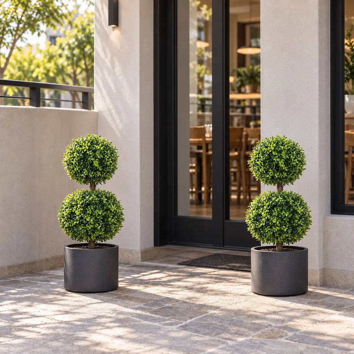 Pair of artificial two ball topiary trees in matching patio planters