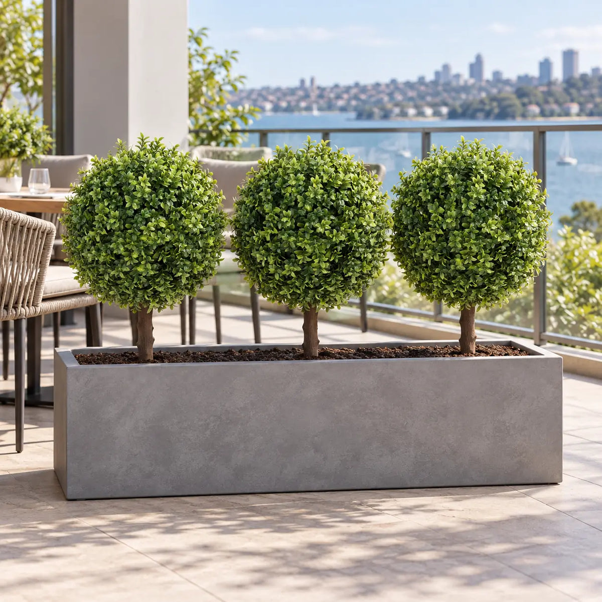 Three artificial single ball topiaries in a long balcony trough planter