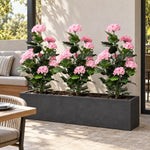 Three artificial pink hydrangea trees in a long trough planter on an outdoor terrace