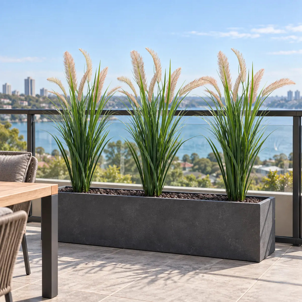 Three artificial reed grass plants in a long outdoor trough planter