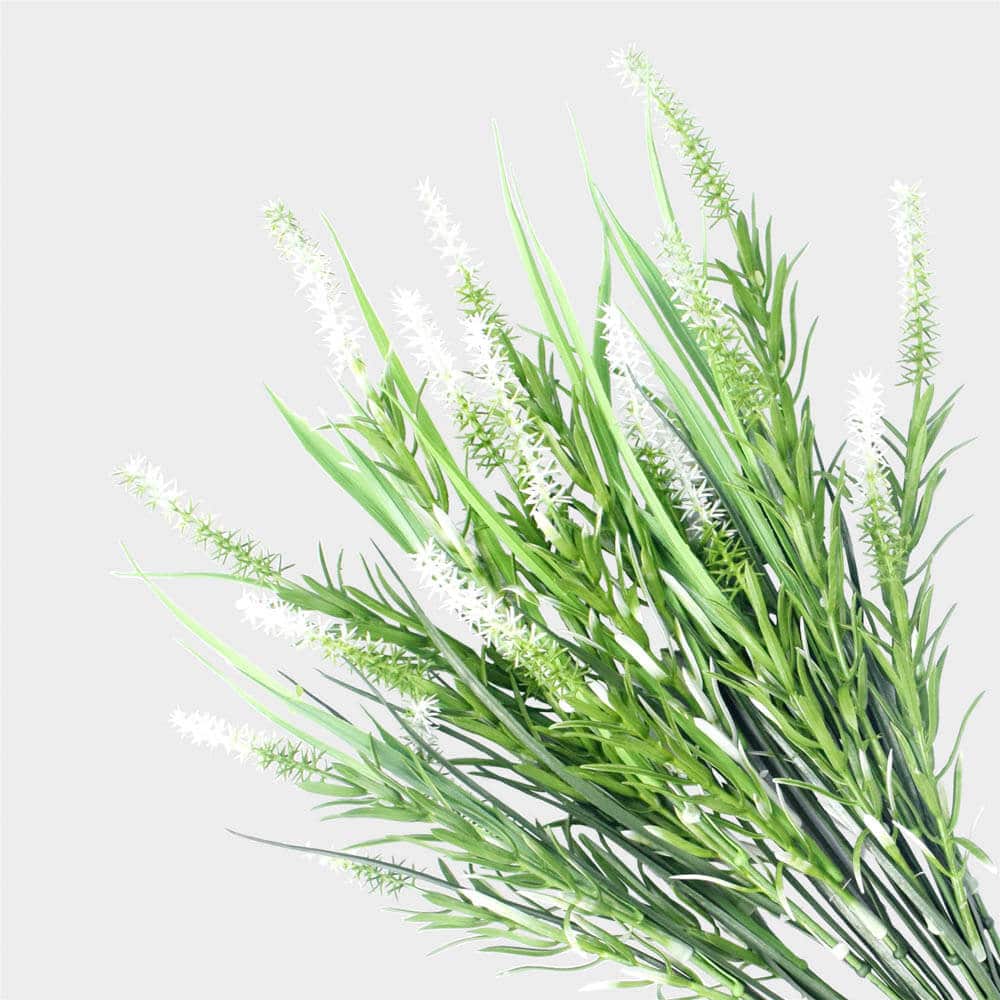 Artificial green plant with white flowers on a light gray background