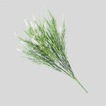 Artificial green plant branch with white flowers on a light gray background