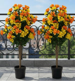 Two potted artificial plants with orange and yellow flowers on a balcony.
