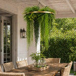Hanging green plant chandelier above a wooden dining table outdoors.