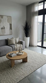 Modern living room with gray sofa, wooden coffee table, and large window.