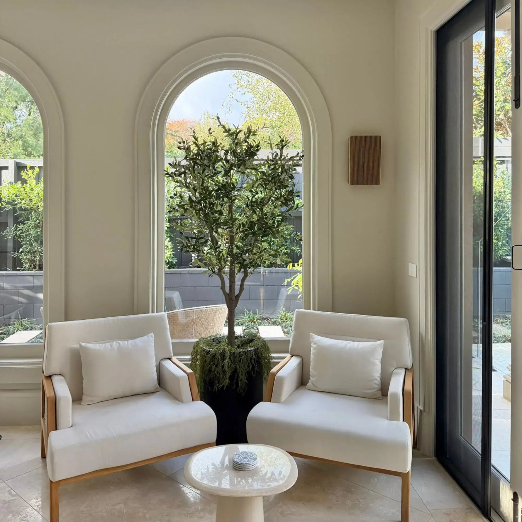 Modern patio with white chairs, a small table, and a potted tree.