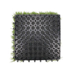 A square black plastic modular pond liner or drainage mat with circular perforations, shown from above on a white background with green grass-like material visible around the edges.