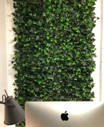 Artificial green wall panel with a laptop and lamp in front