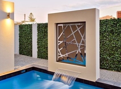 Modern poolside design with geometric wall art and water feature.