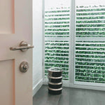 Modern bathroom with a stack of black and silver cylindrical objects near a glass door with green pattern.