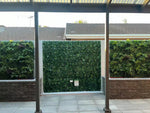 Patio area with glass panels, green hedges, and tiled floor.