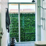 Modern bathroom with a glass shower enclosure featuring artificial greenery.