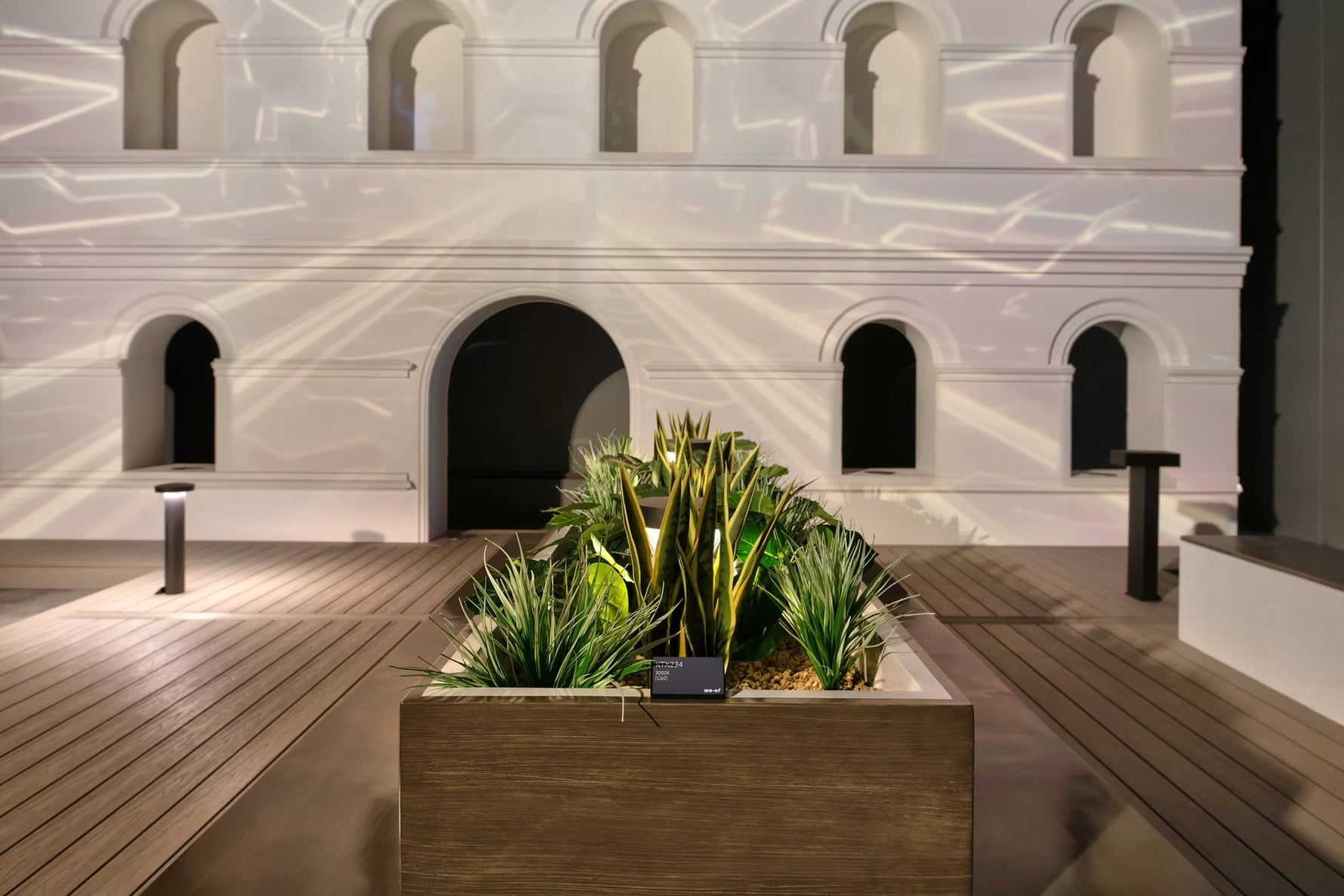 Decorative planter with greenery in front of a building with arches