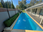Swimming pool with a house and garden in the background