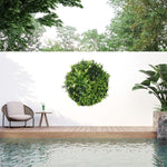 Outdoor setting with a pool, chair, table, and decorative green bush on a white wall.
