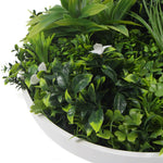 Artificial greenery with white flowers in a white container on a white background
