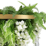 Decorative arrangement of green ferns and white flowers with a gold accent on a white background
