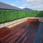 Wooden deck with a bench and artificial greenery in the background