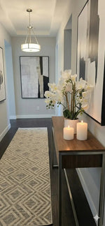 Modern hallway with a console table, candles, and decorative plants.