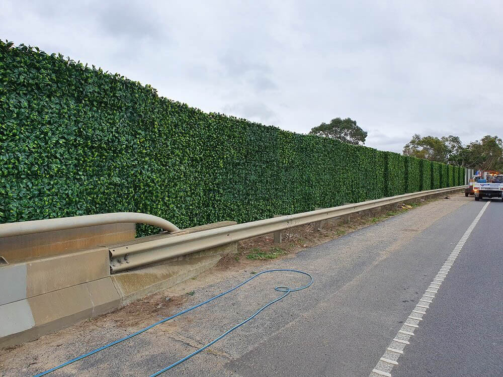Road with a guardrail and green hedge on a cloudy day