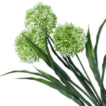 Artificial green and white flower arrangement with long green leaves on a white background