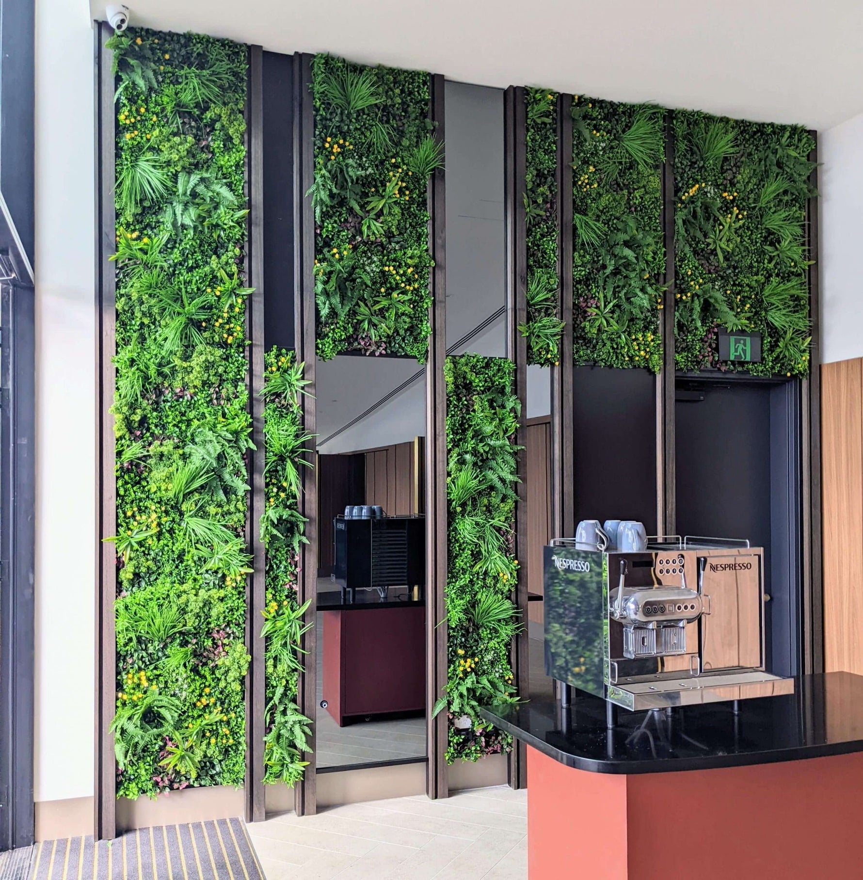 Modern kitchen with a vertical green wall and coffee machine.