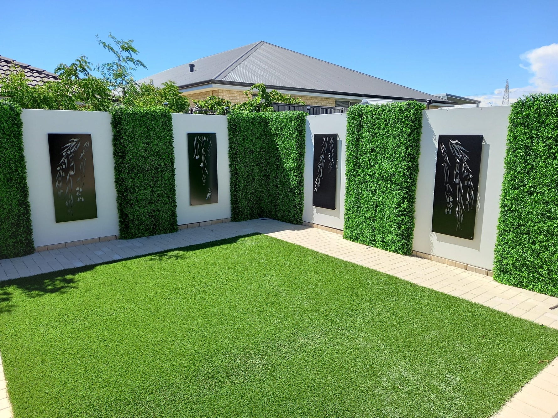 Garden area with artificial grass, decorative walls, and framed artworks.