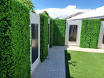 Garden with artificial hedges and a white house in the background