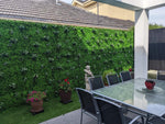 Outdoor patio area with a green wall, table, and chairs.