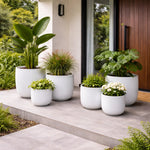 White planters with various plants on a patio area.