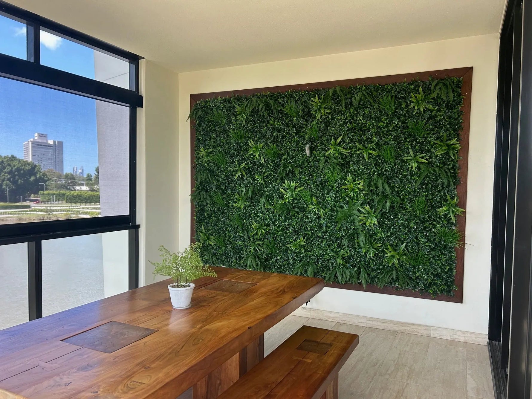 Modern interior with a wooden dining table and bench against a living wall.