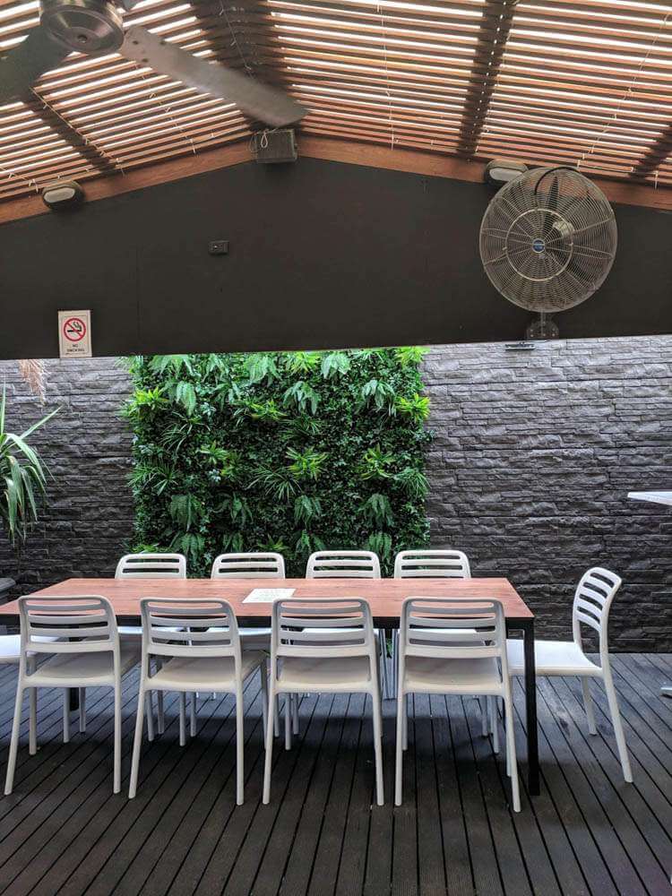 Outdoor dining area with a long table and chairs under a large canopy.