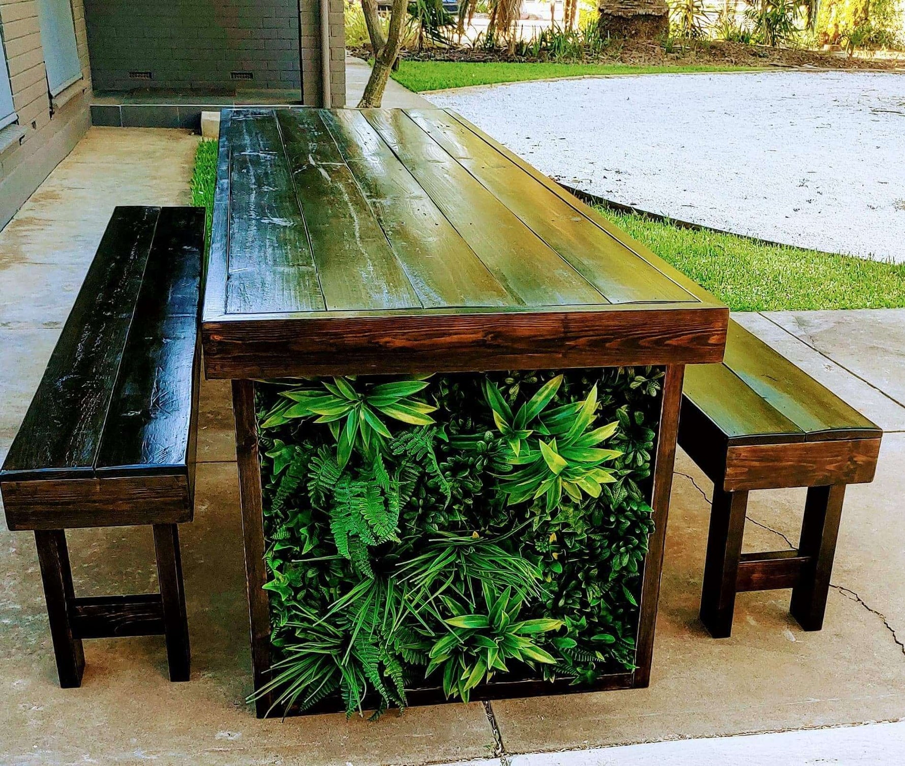 Wooden outdoor table with greenery and benches in a garden setting
