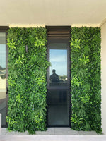 Living green wall with a door in the center, reflecting a person.