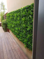 Artificial green wall panel on a building exterior with wooden deck below