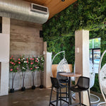 Modern interior with a small table and chairs against a wall with decorative plants and flowers.