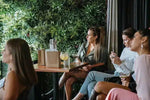 Group of women sitting at a table with drinks in an outdoor setting