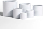 Set of white ceramic planters of various sizes on a light gray background