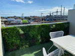 Outdoor patio area with white furniture and greenery, overlooking a construction site.