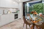 Modern kitchen with dining area featuring a glass table and chairs.