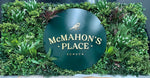 Green sign with 'McMahon's Place Echuca' surrounded by artificial plants