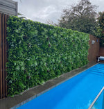 Green artificial hedge wall next to a pool