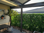 Patio area with a pergola, table, and plants in a residential setting