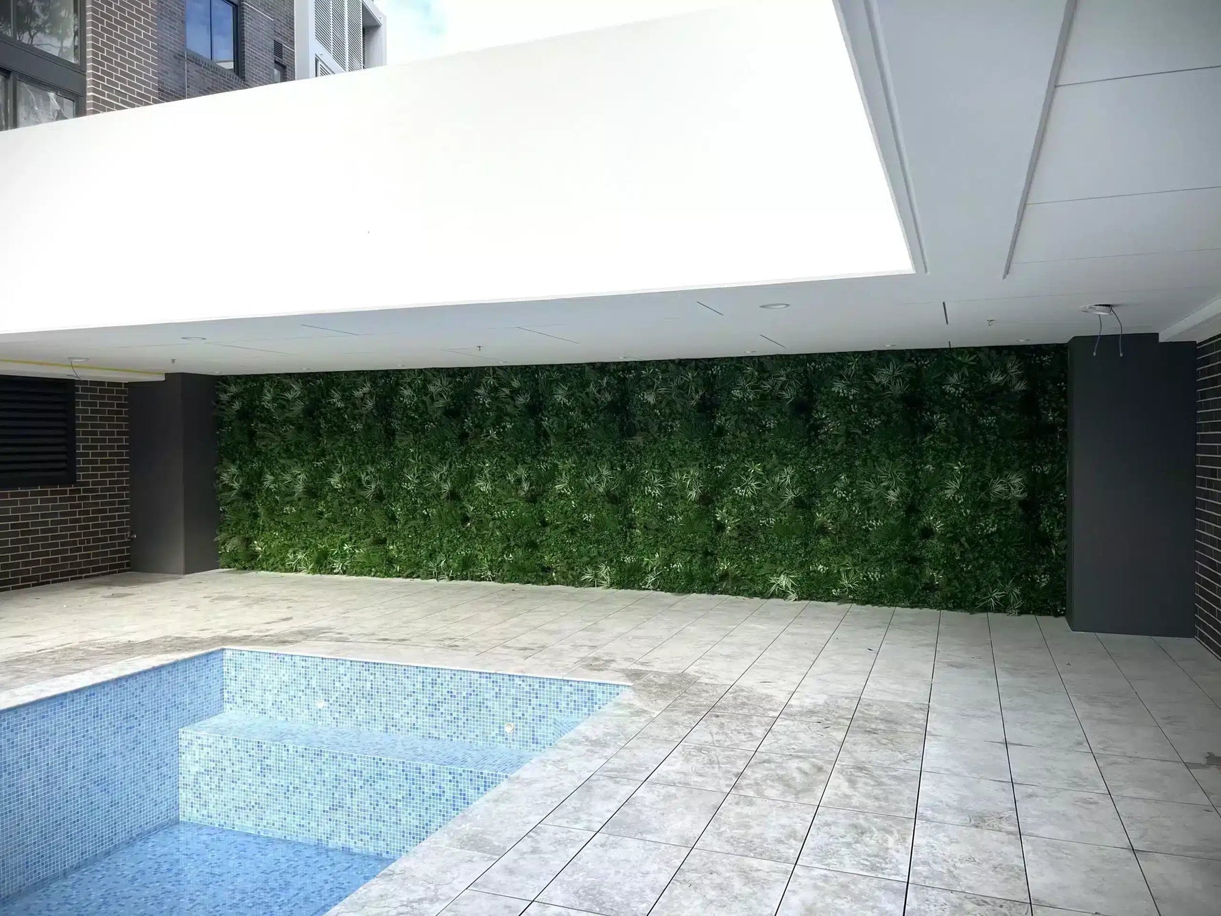 Modern outdoor area with a pool and green wall