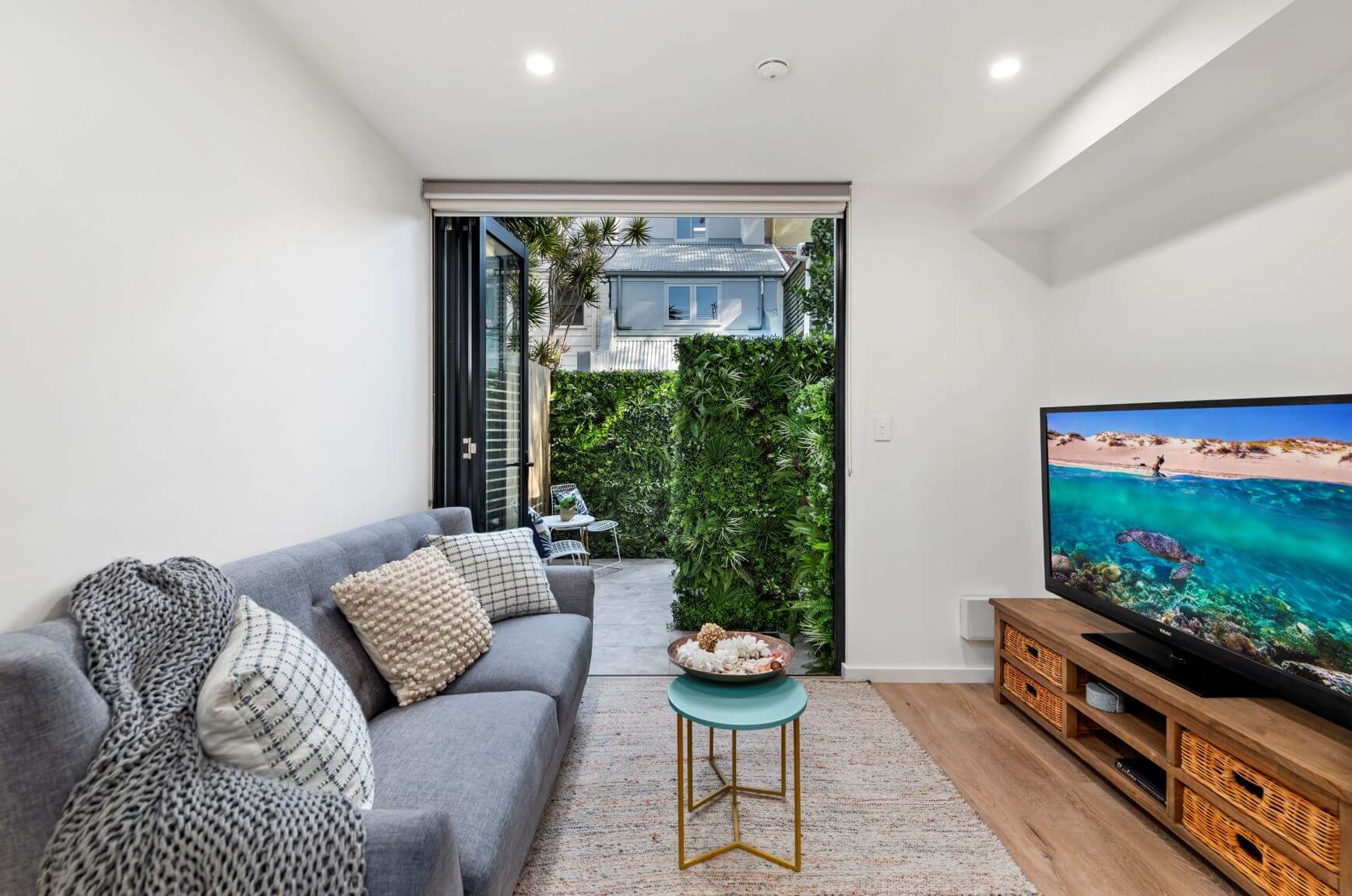 Modern living room with a gray sofa, TV, and outdoor view.