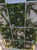 Artificial green wall with grid pattern and white flowers