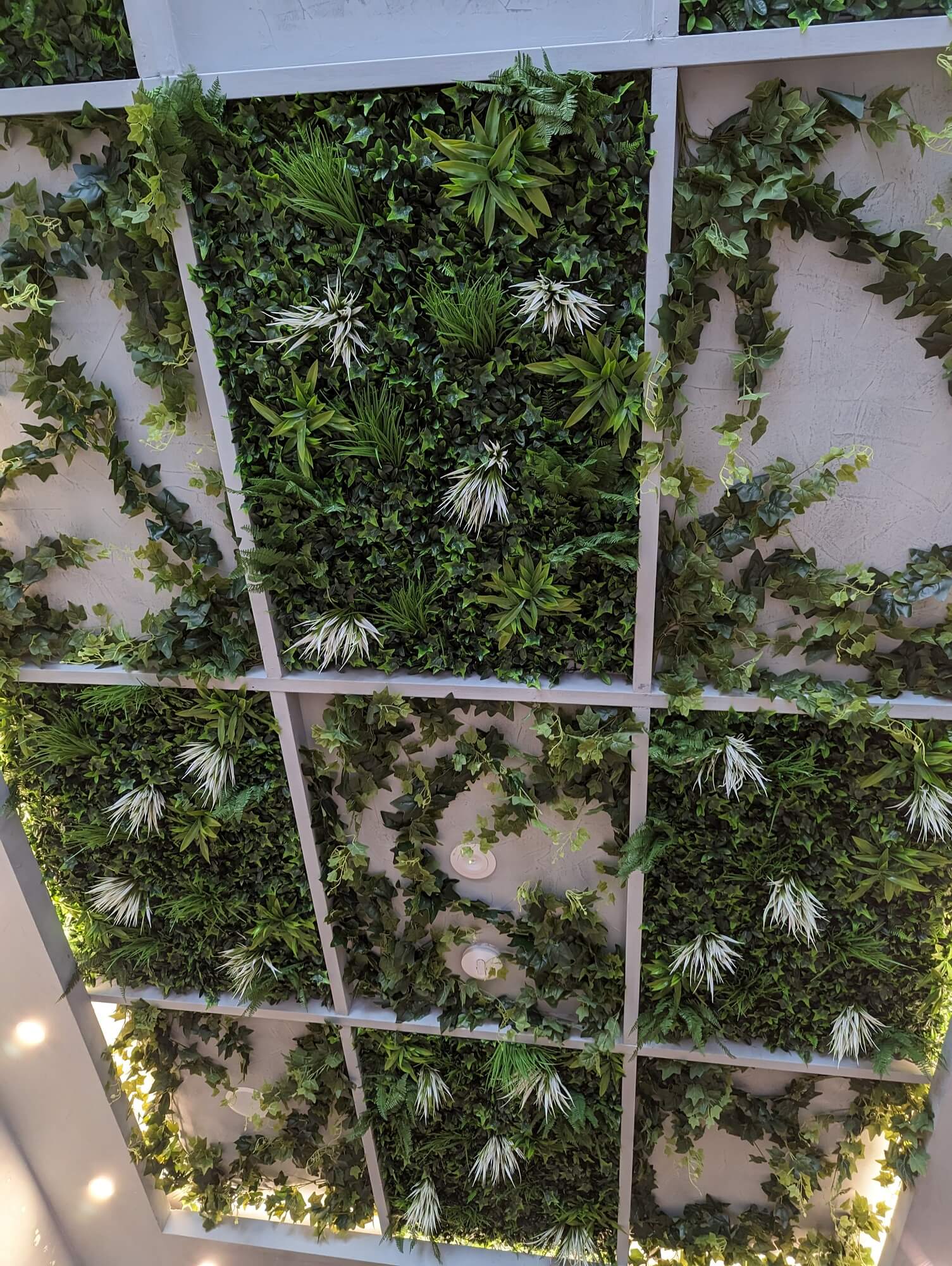 Artificial green wall with grid pattern and white flowers