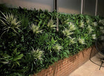Artificial green wall with plants against a brick wall