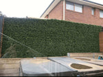 Artificial hedge installed behind a house with a patio area in the foreground